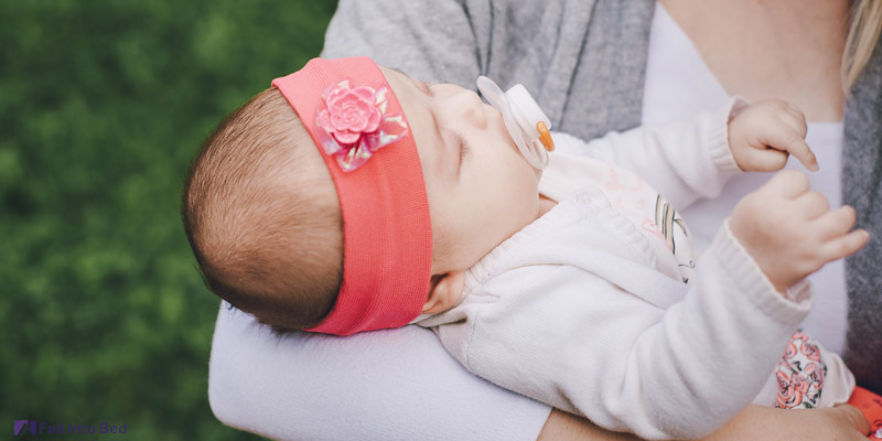 baby sleeping in mom's arms