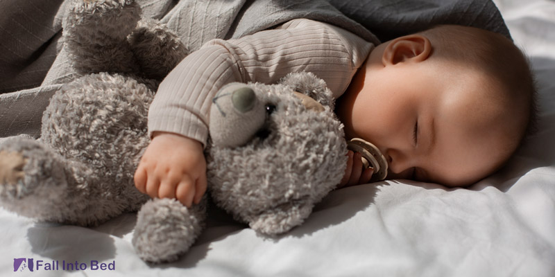 baby sleeping with stuffed animal in his crib